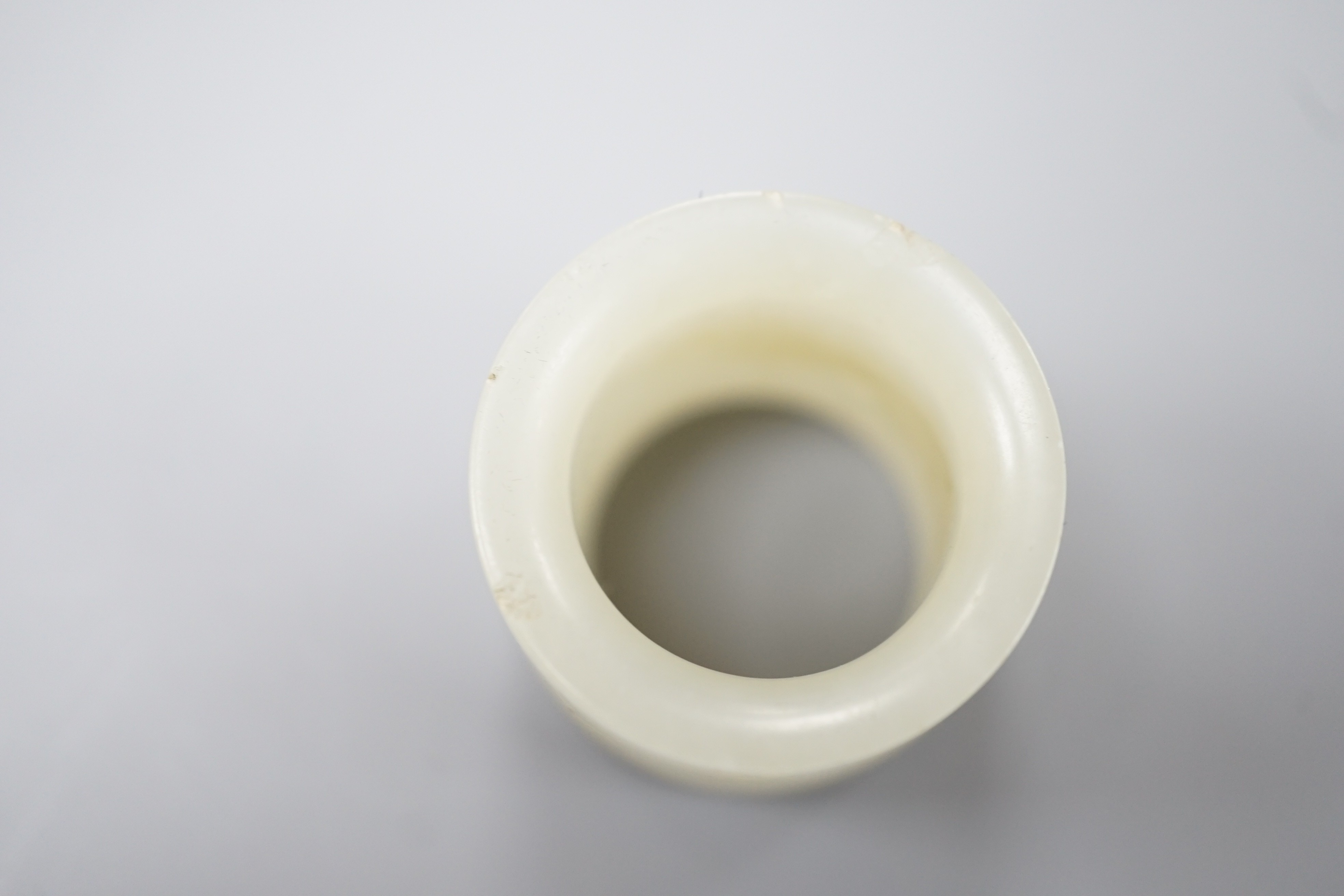 A 19th century Chinese pale celadon jade archer’s thumb ring, inscribed, 3 cm diameter